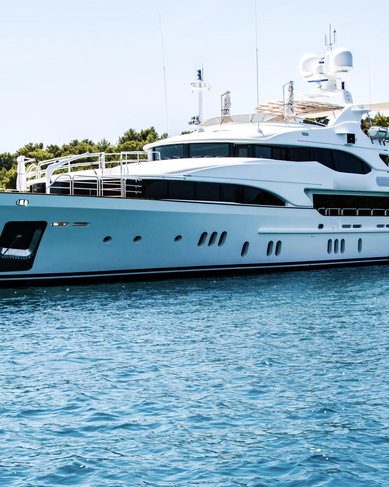 A white superyacht moored in a sheltered bay