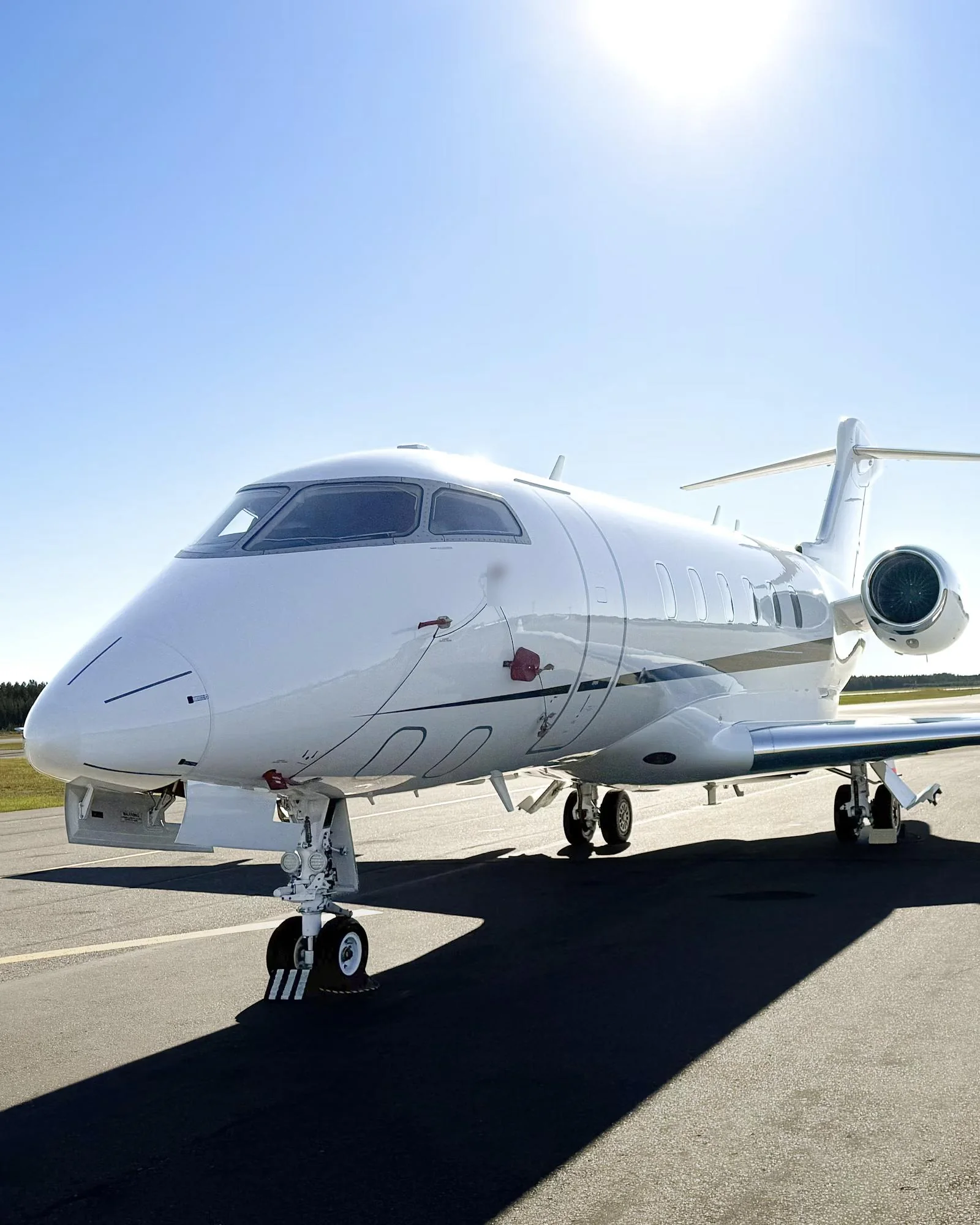 A white private jet on the apron under a clear sky
