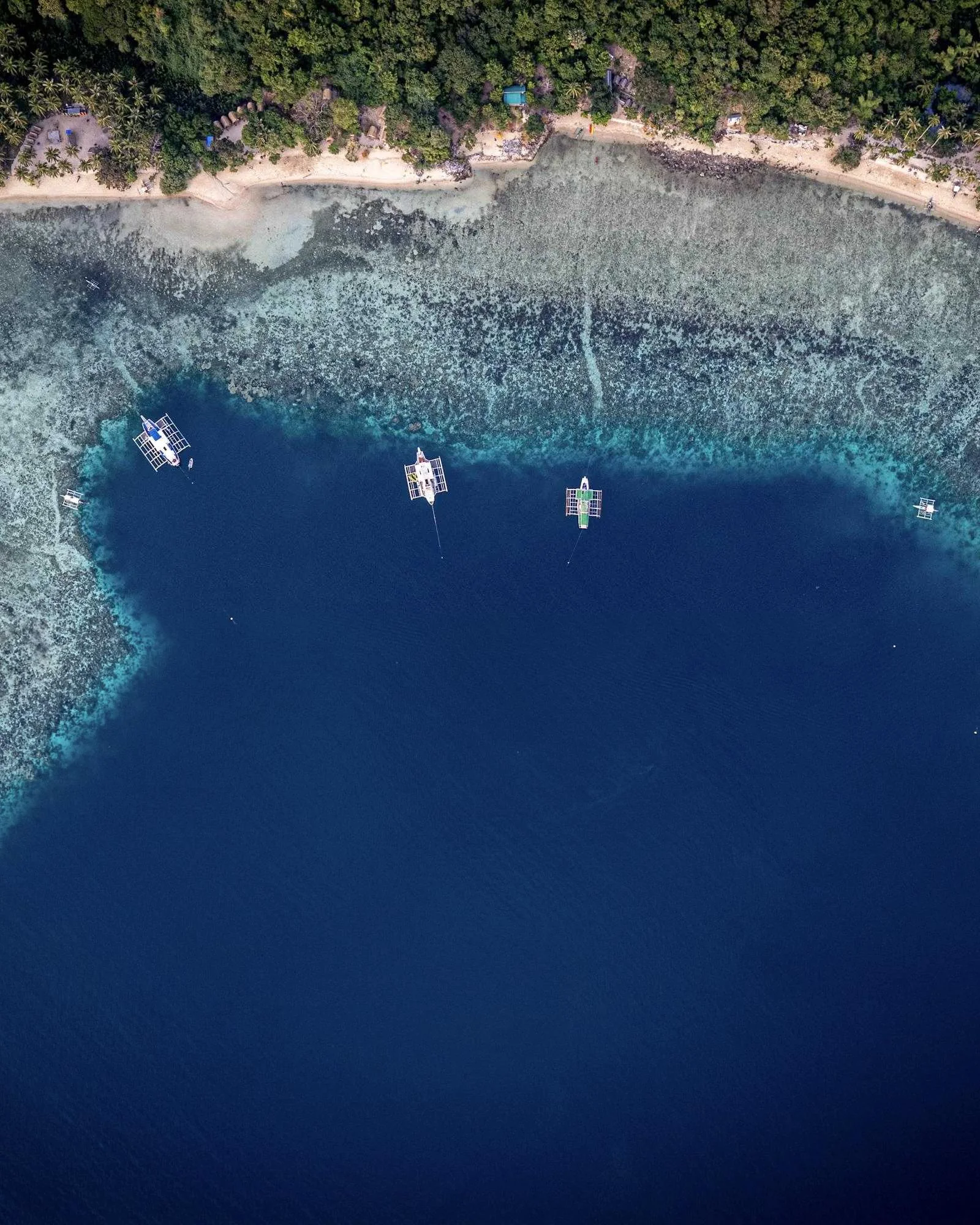 An aerial view of boats anchored off a tropical reef