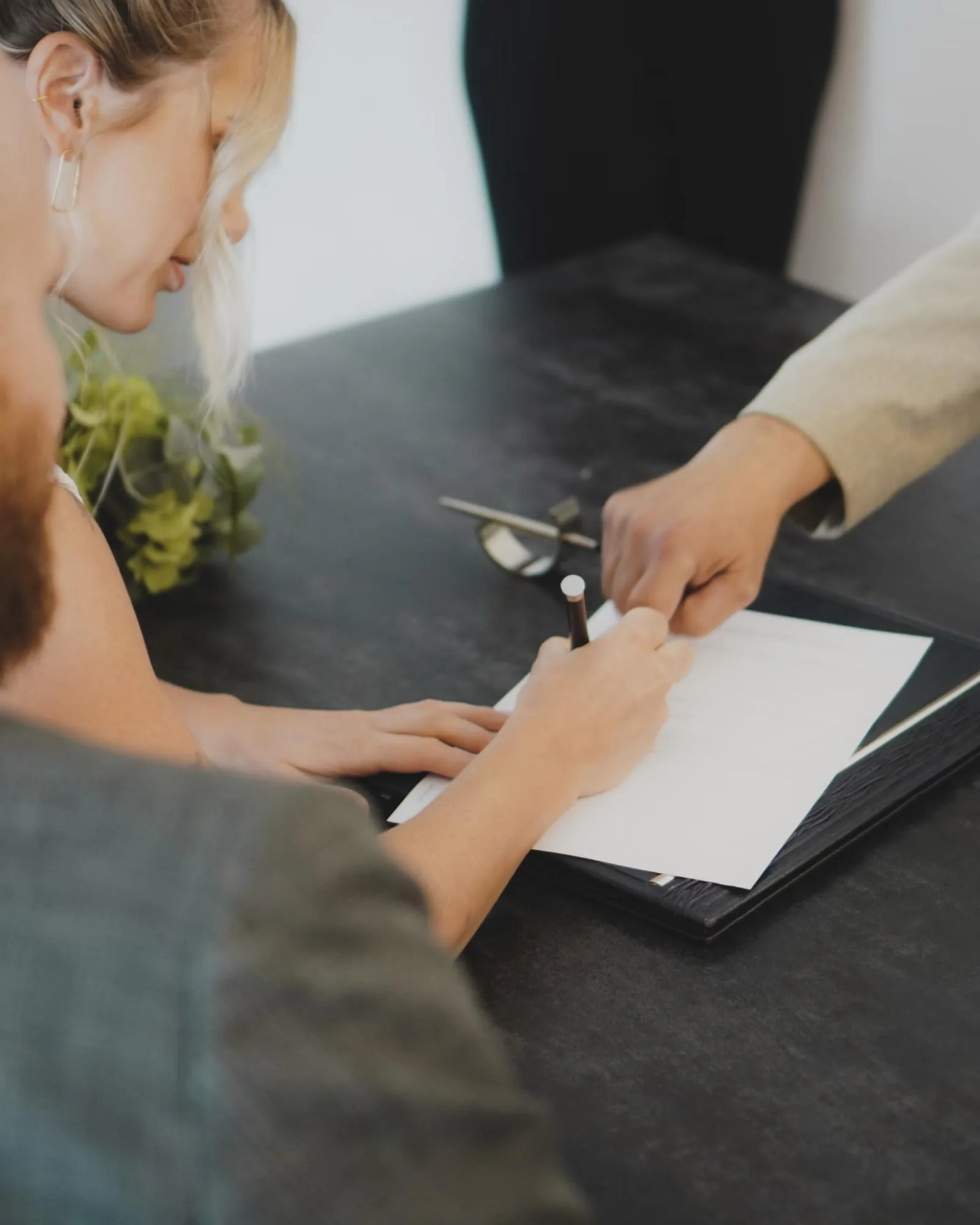 Two people signing a document at a desk