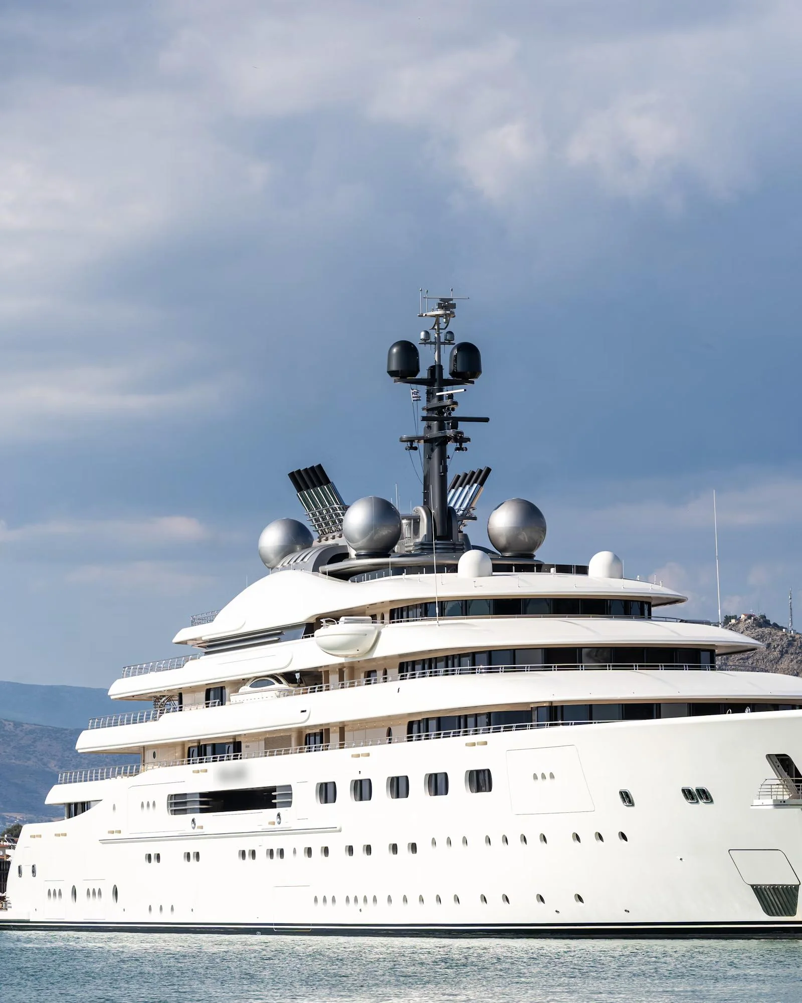 A superyacht moored in a bay below wooded hills