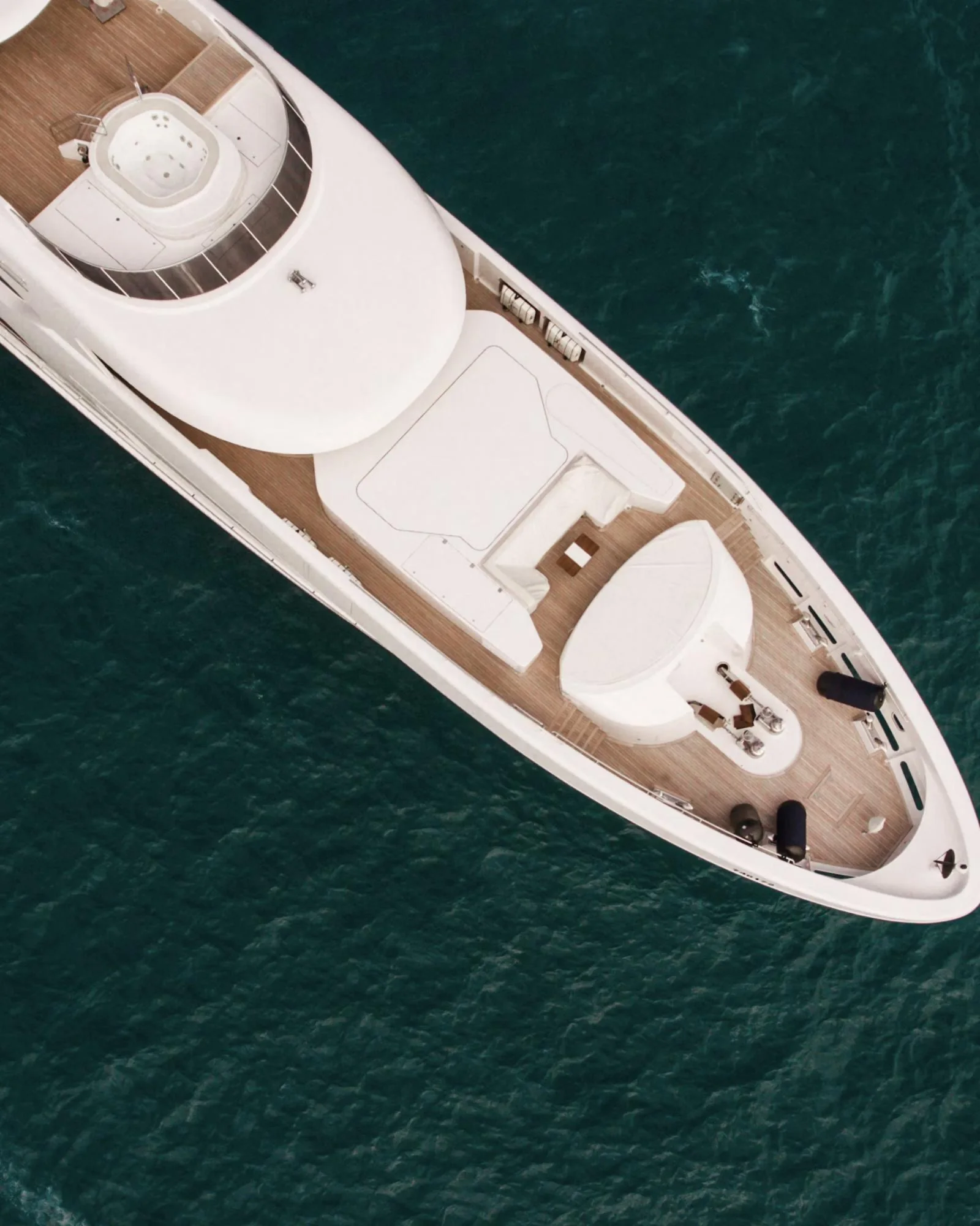 A white superyacht seen from above on dark blue water